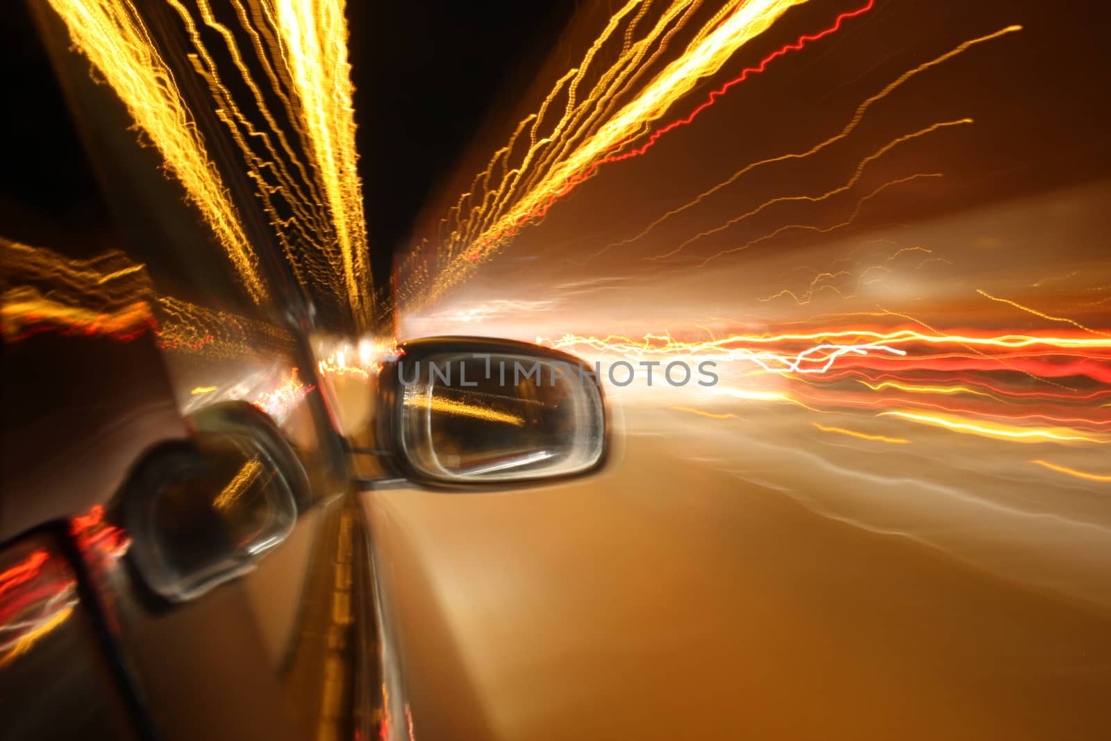 An abstract photo of a car mirror speeding through a tunnel with lights.