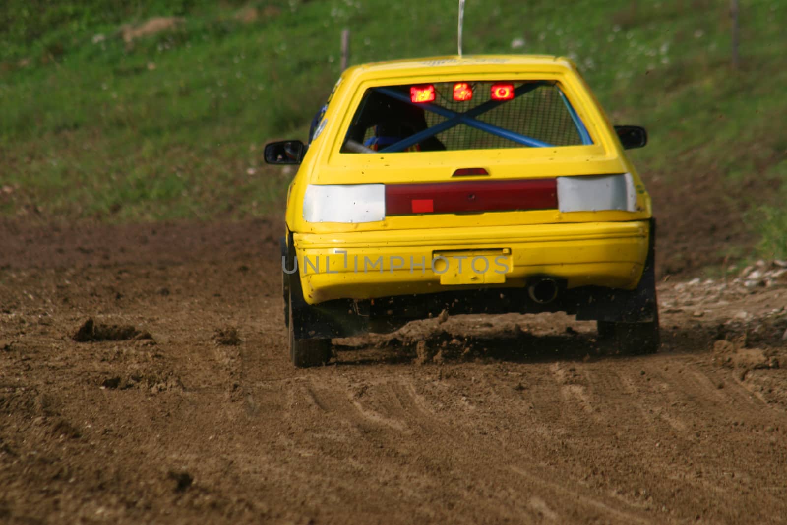 Yellow car on track going fast and throwing dirt in the air