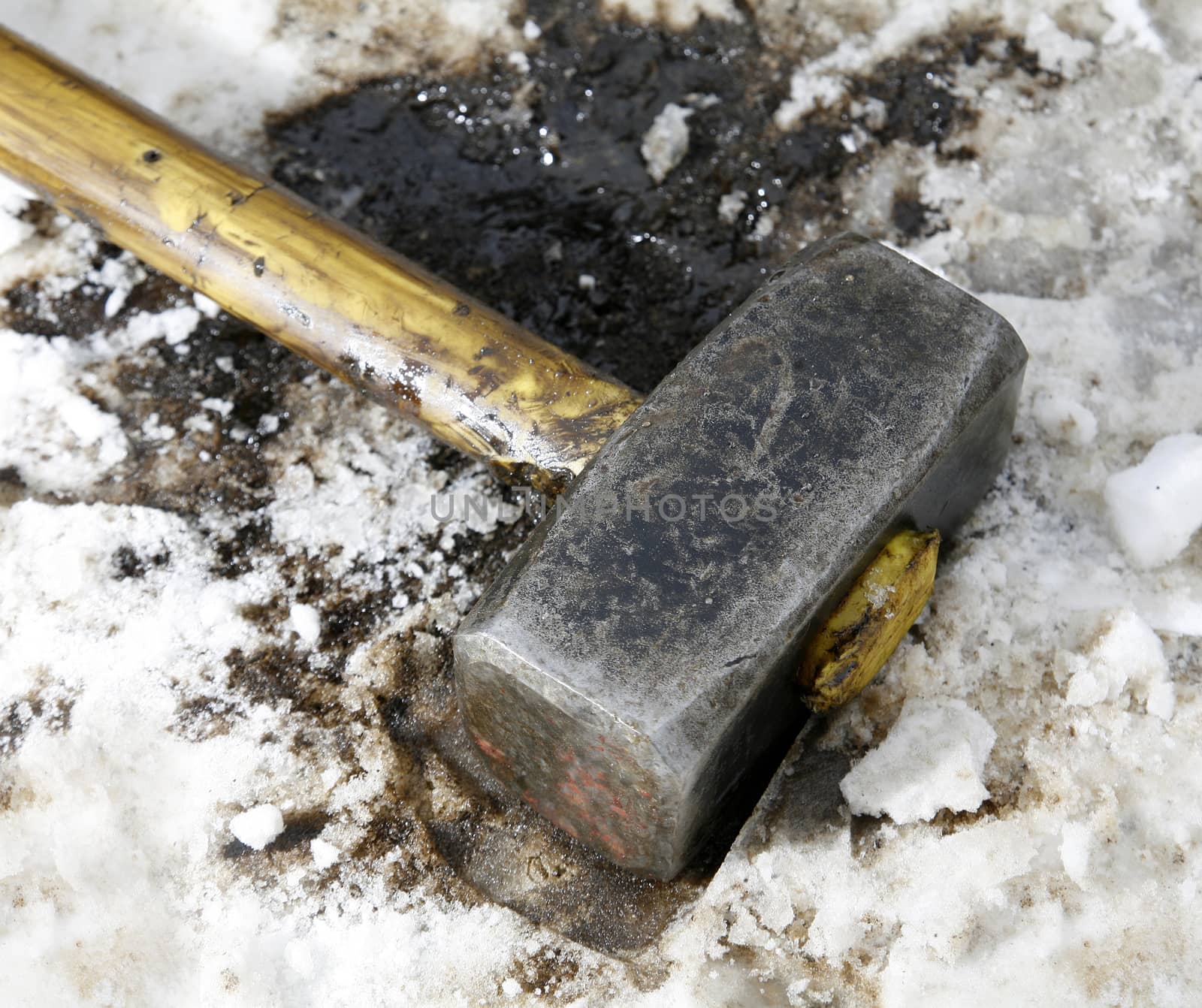 Sledgehammer covered in oil lies in the snow
