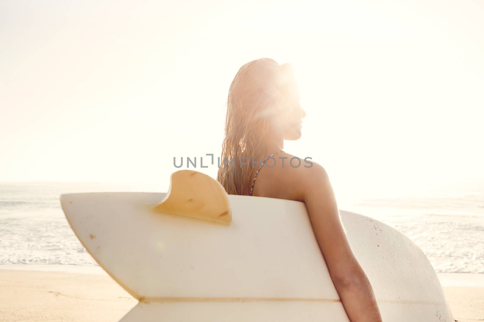 Beautiful young woman holding her surfboard after a day of surf