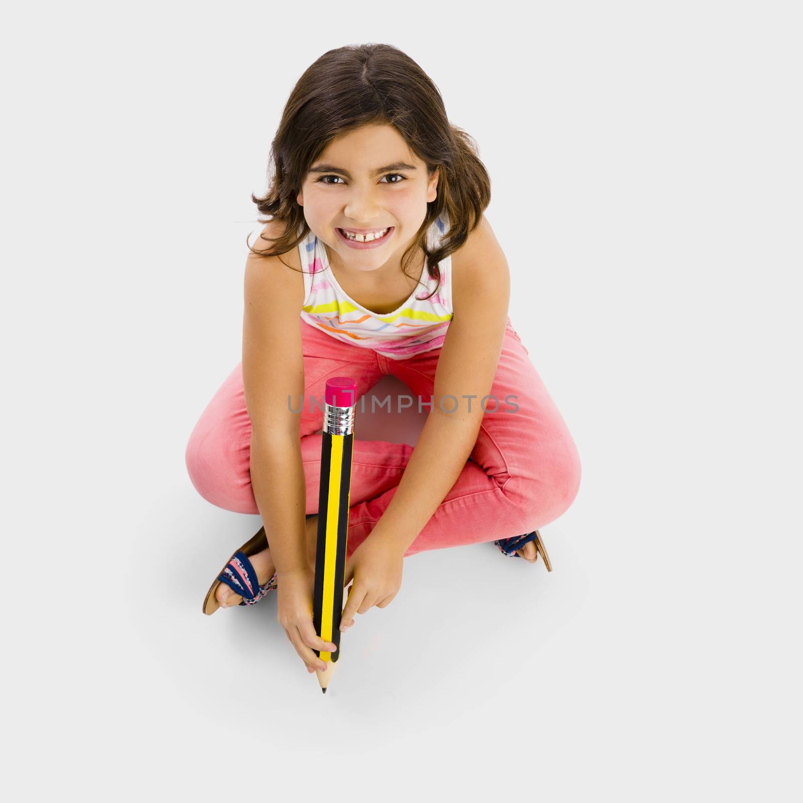 Little girl making a drawing with a big pencil in the floor