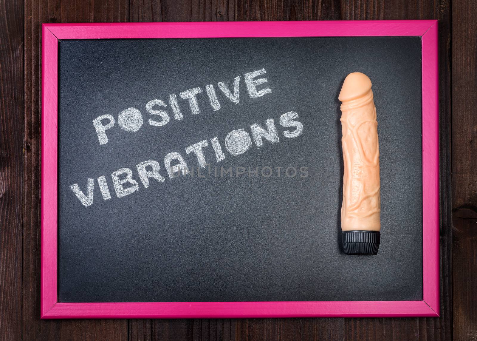 In the picture a vibrator on a blackboard with the words "positive vibrations" on the left and in the background old wood