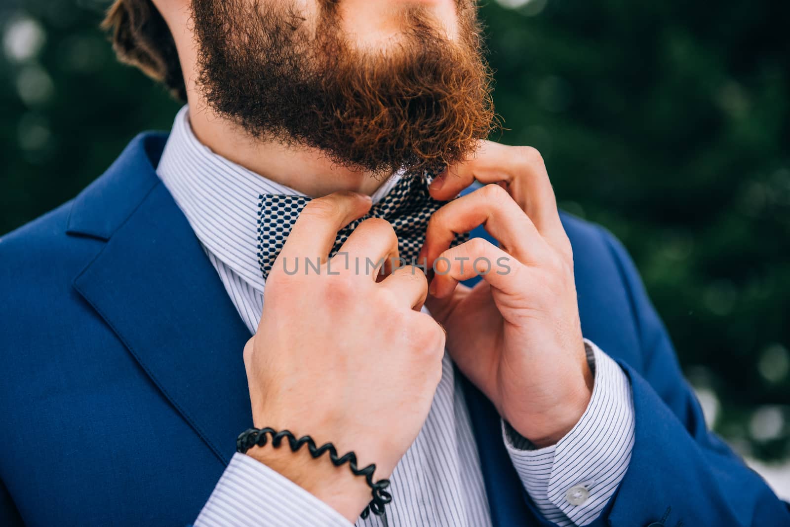 groom in a blue suit and bride in white, embroidered with blue pattern, dress on a background of green pine forests in the mountains of the Carpathians