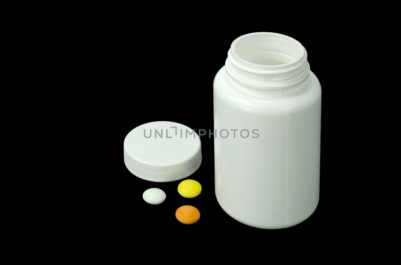 three pills of a different colors with white jar on a black background