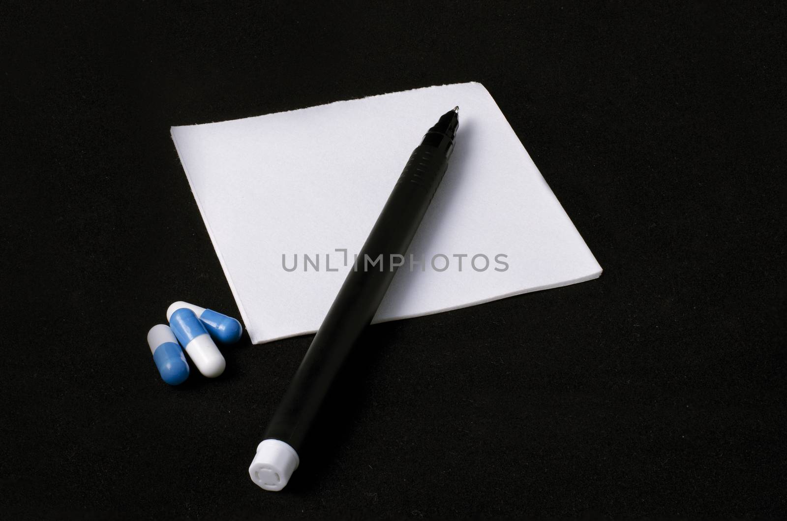 prescription, pills and pen on a black background
