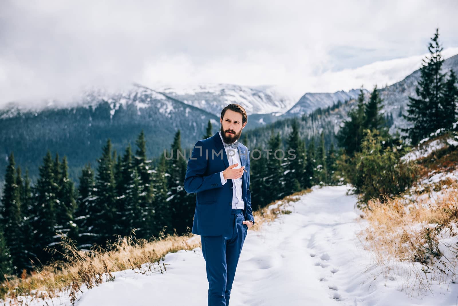 groom in a blue suit and bride in white, embroidered with blue pattern, dress on a background of green pine forests in the mountains of the Carpathians, smoking, cigar, smoke