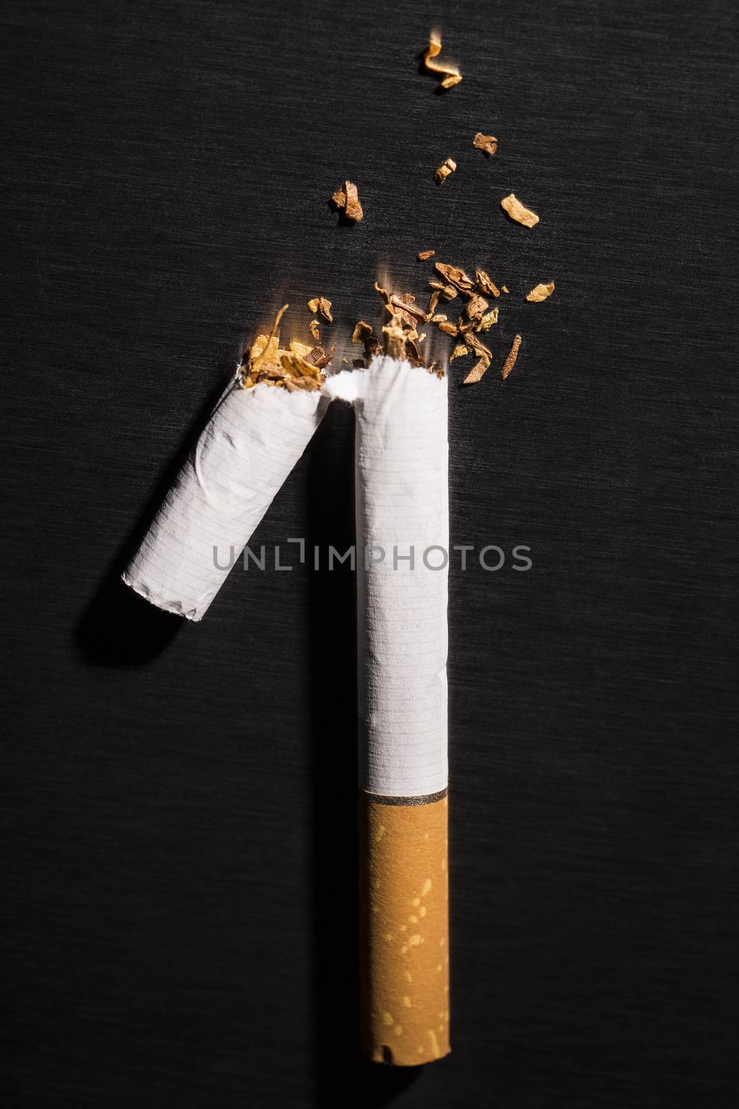 Broken cigarette on black background, reflected, stop smoking