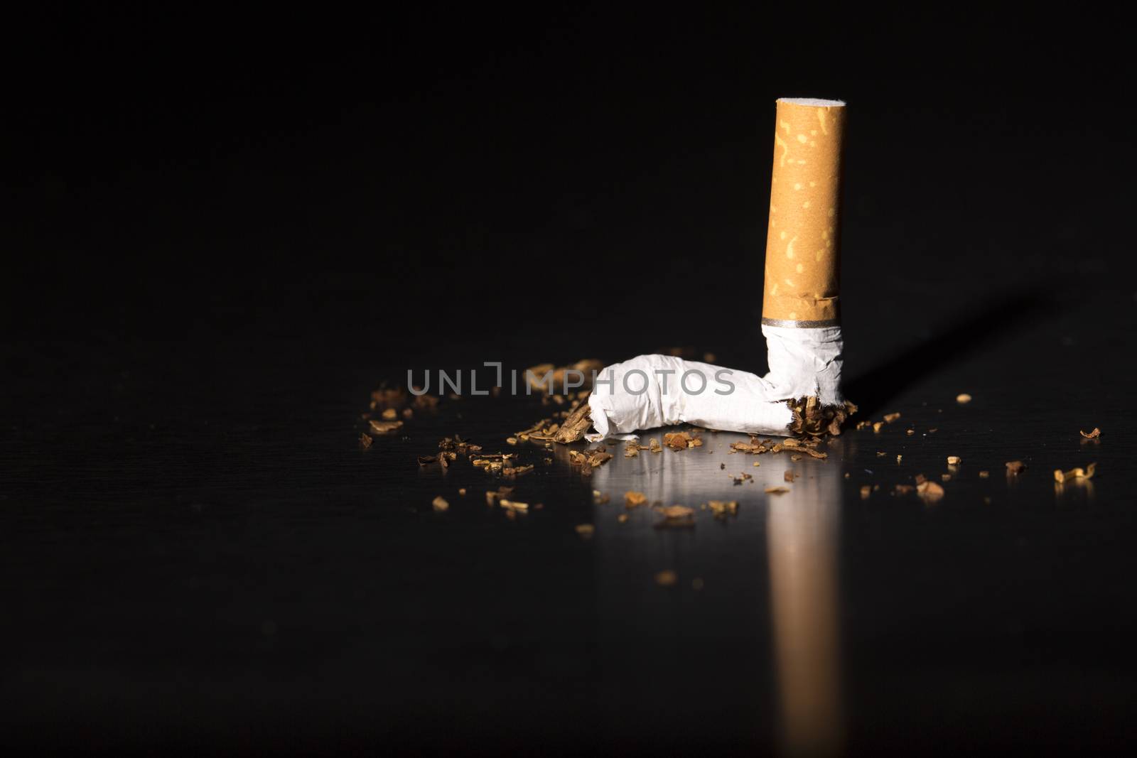 Broken cigarette on black background, reflected, stop smoking