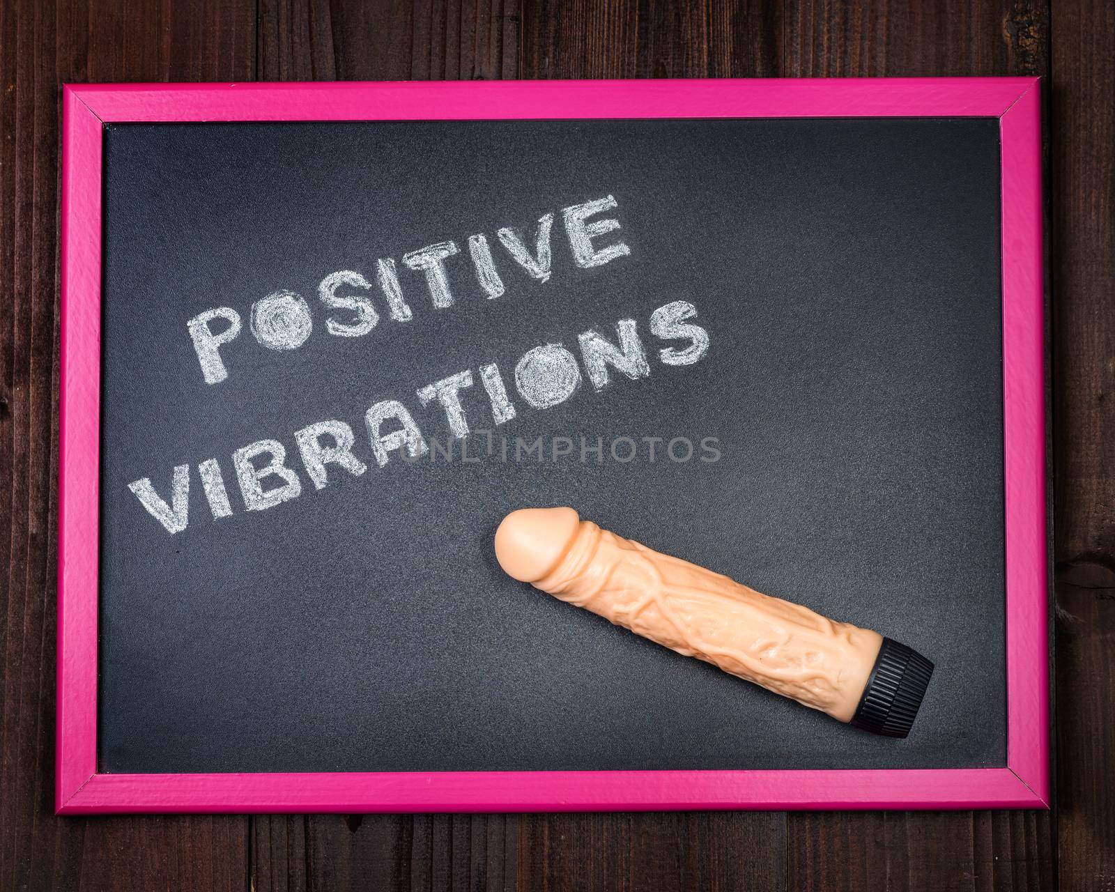 In the picture a vibrator on a blackboard with the words "positive vibrations" on the left and in the background old wood