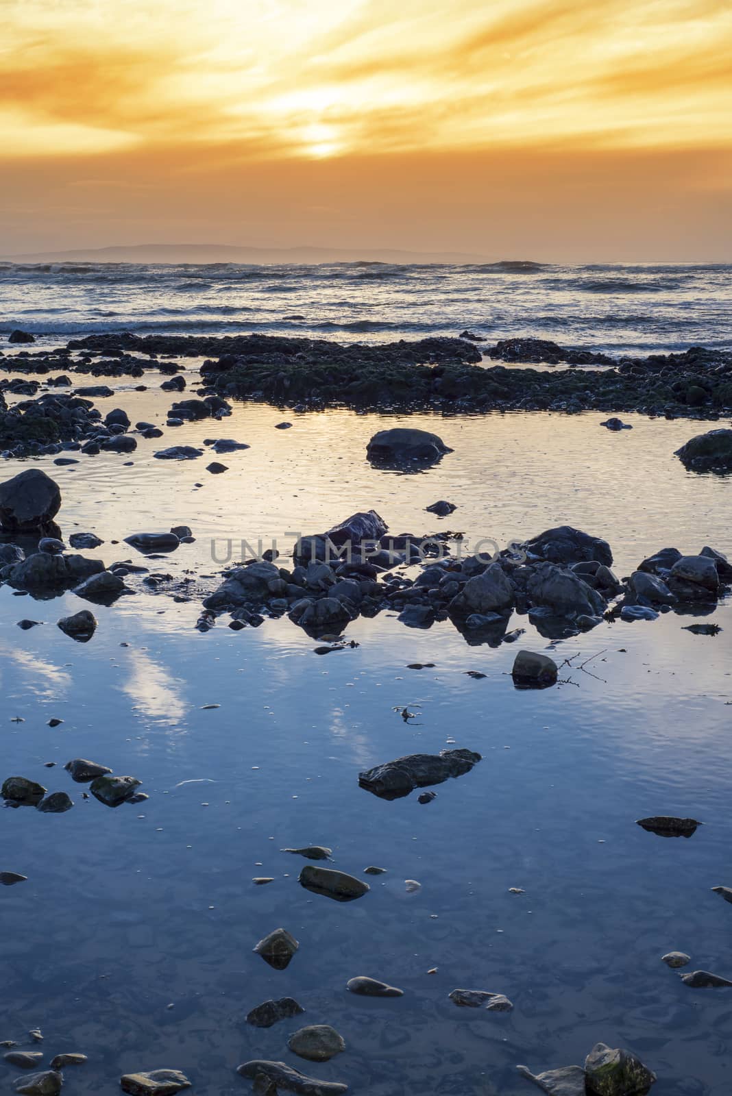 reflections at rocky beach near ballybunion on the wild atlantic way ireland with a beautiful yellow sunset