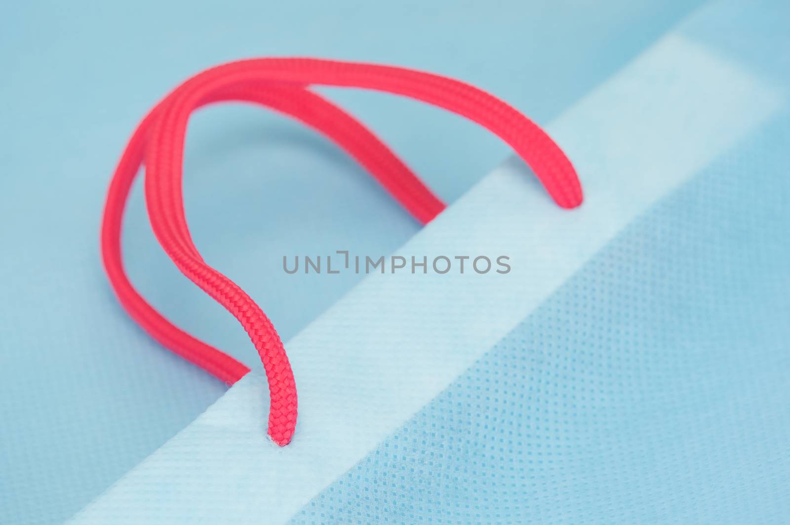 Close up pink rope carry with light blue paper bag.