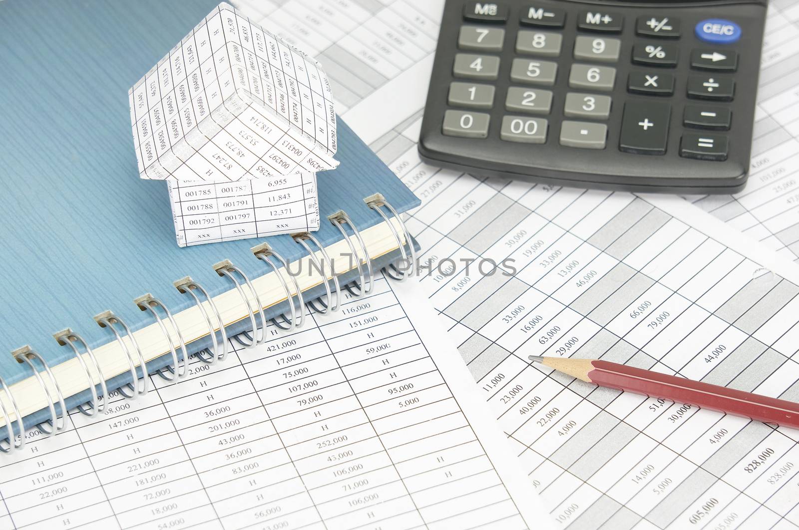 Brown pencil with house on notebook and calculator on finance account as background.