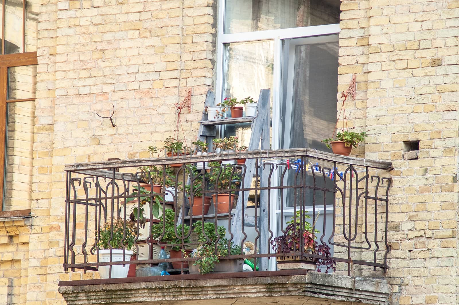 balcony with blooming flowers in a brick house on a sunny day