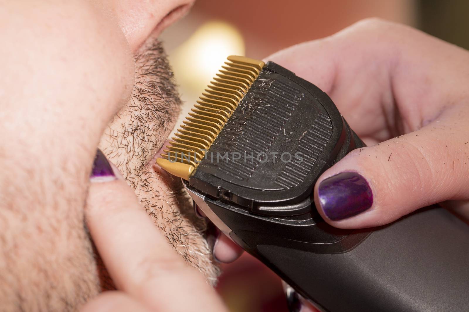Hairdresser, cutting beard in her work place by CatherineL-Prod