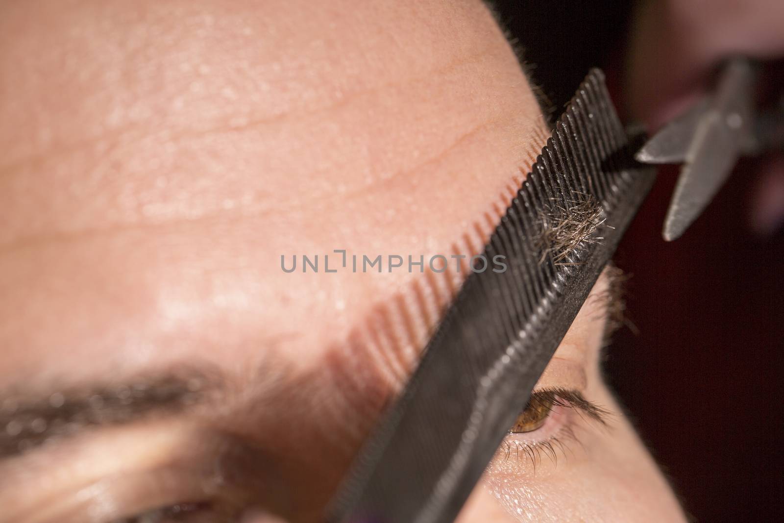 Portrait of man cutting eyebrow hairs. by CatherineL-Prod