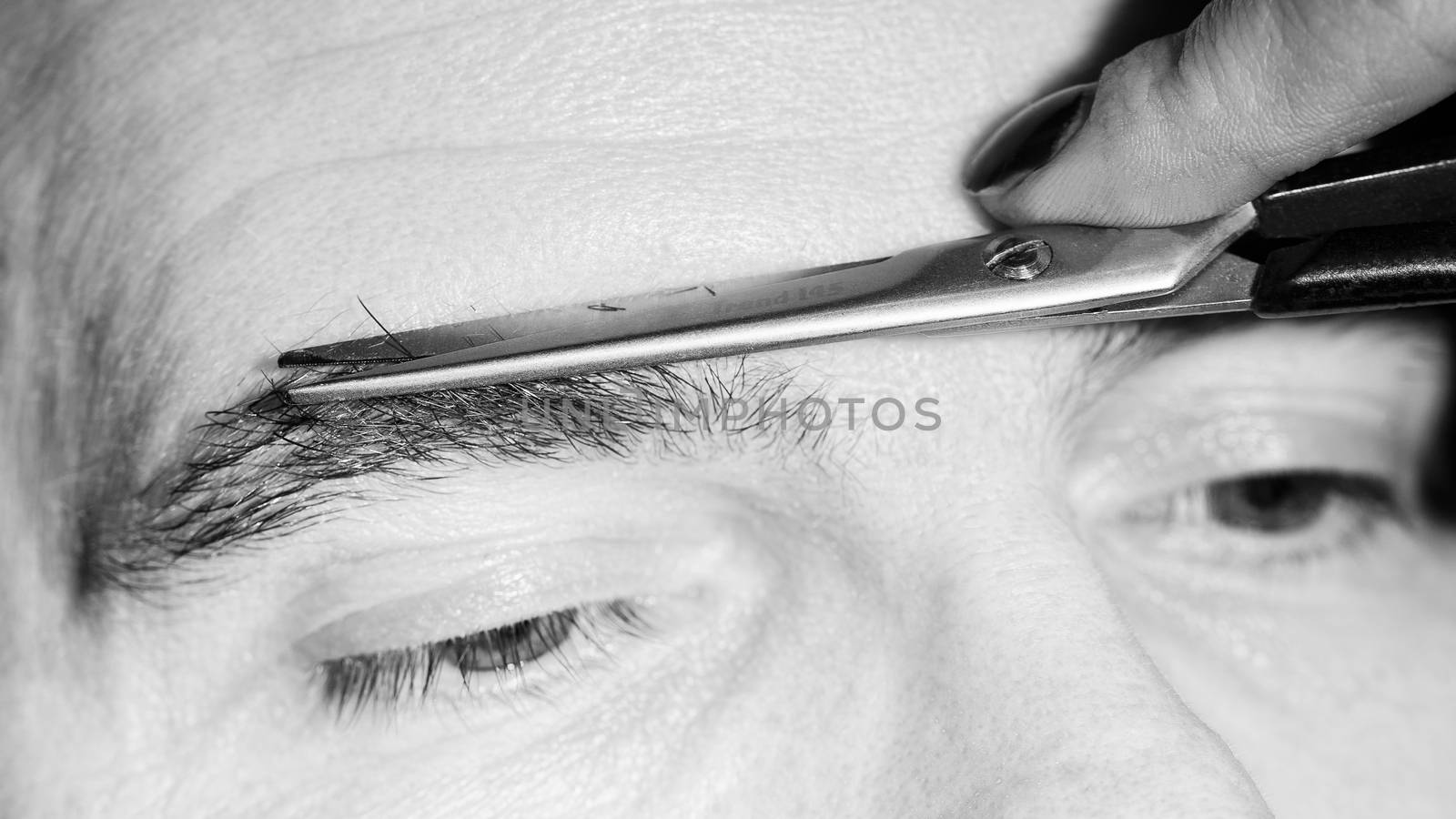 Portrait of man removing eyebrow hairs with scissors