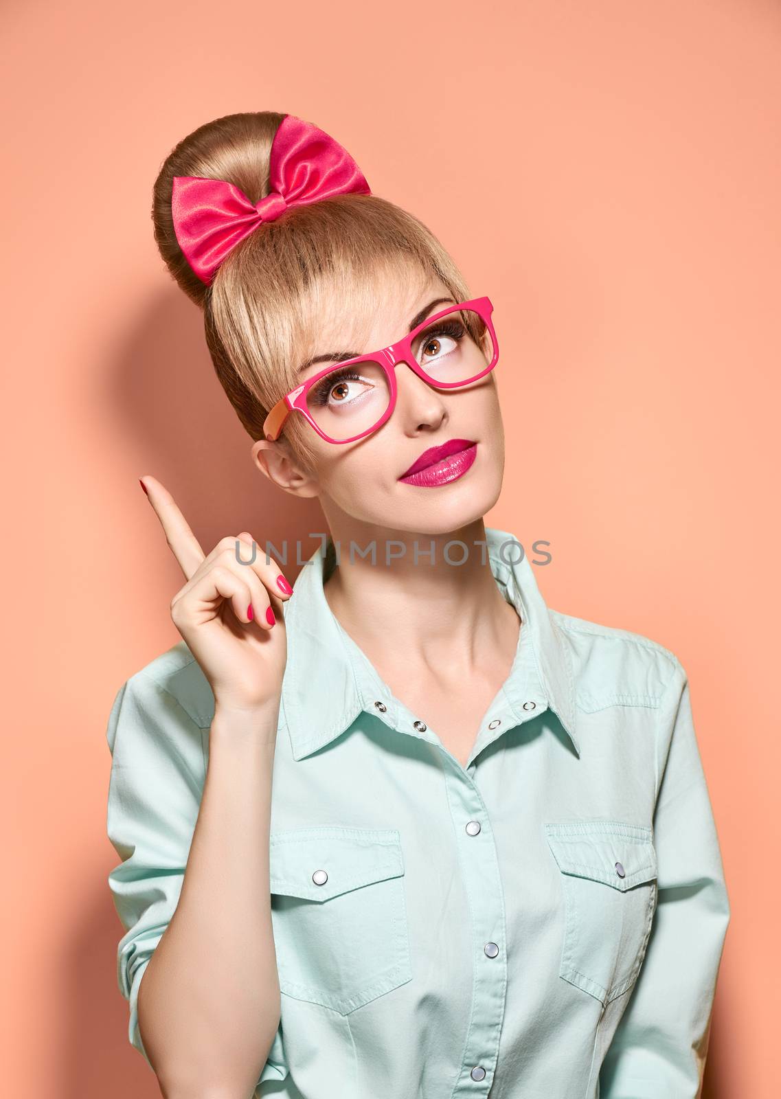 Beauty fashion hipster woman in stylish glasses thinking, idea. Attractive pretty funny blonde girl smiling. Confidence, success, Pinup hairstyle bow makeup. Unusual playful, expression.Vintage, pink