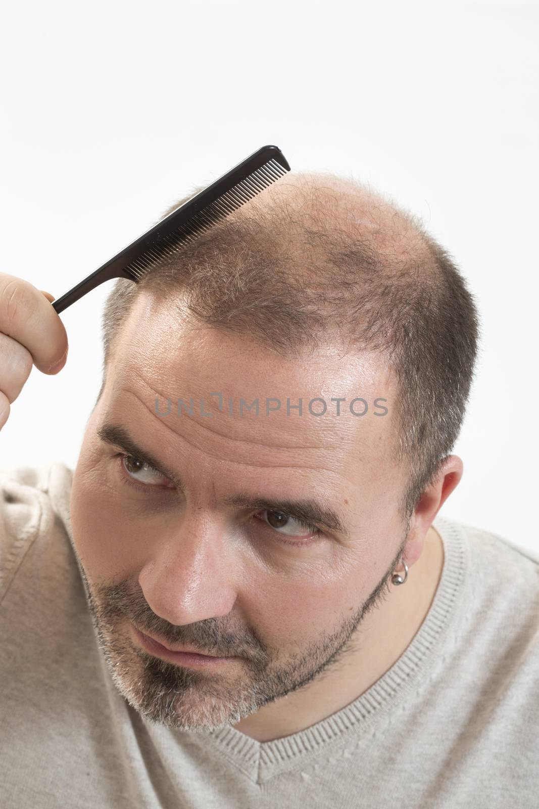 adult man hand holding comb on bald head by CatherineL-Prod