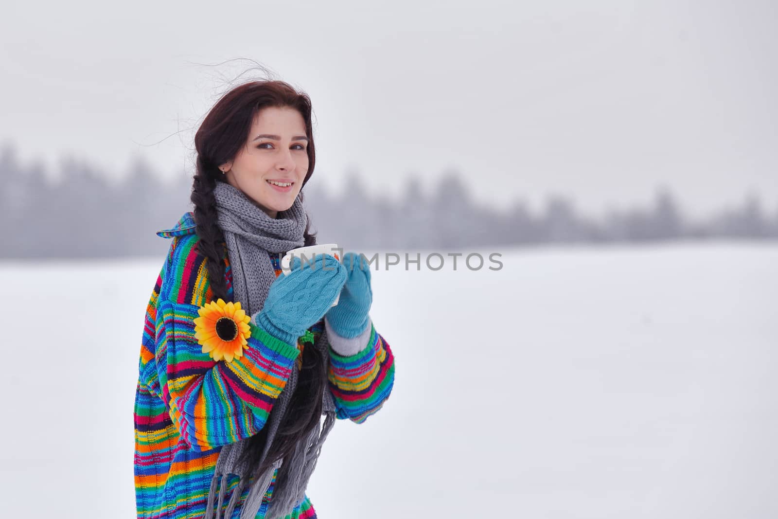 Beautiful girl in a sweater on a winter walk with a cup of coffee
