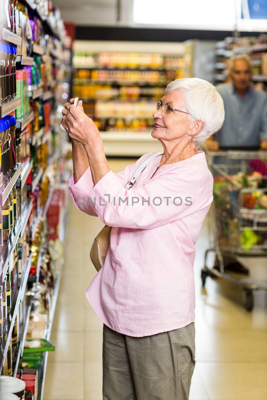 Senior woman taking a picture of product on shelf by Wavebreakmedia