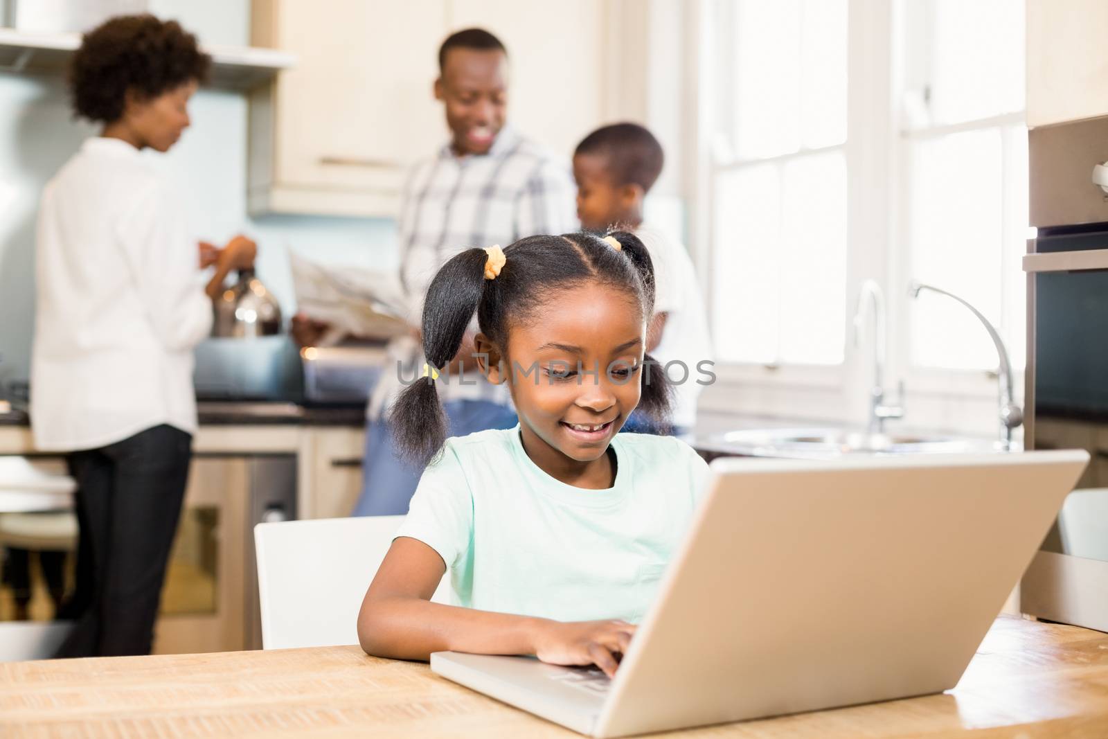 Daughter using laptop in the kitchen by Wavebreakmedia