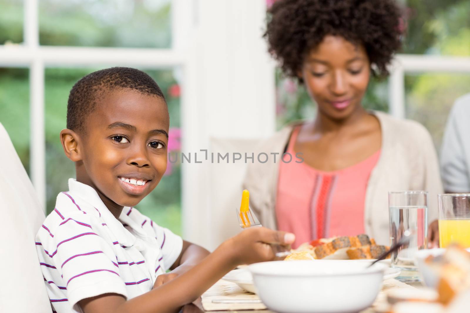 Smiling son eating his dinner with family