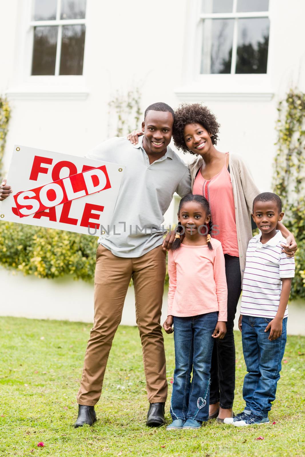 Happy family standing together while holding a sold sign