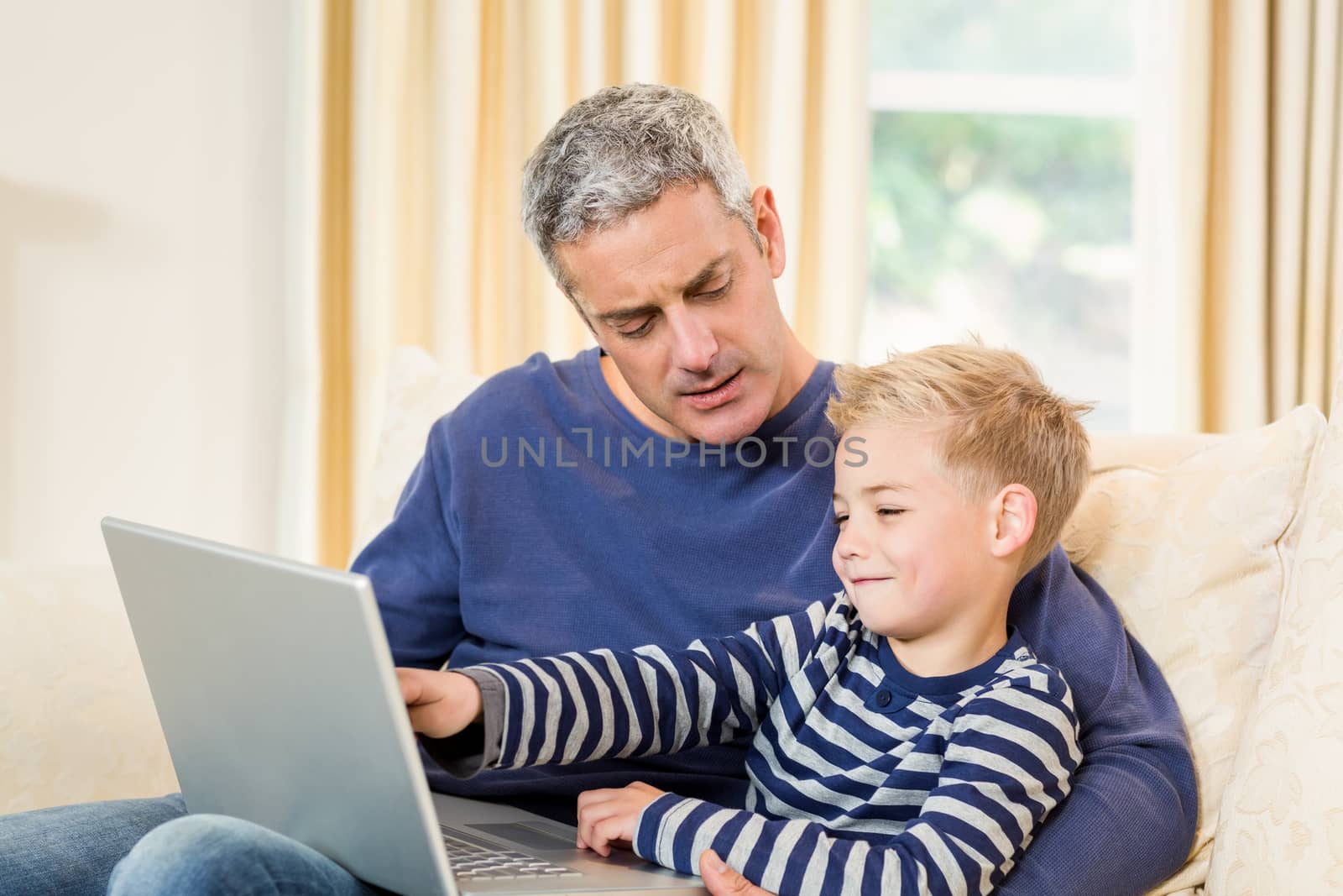 Father and son using laptop on the sofa in living room 
