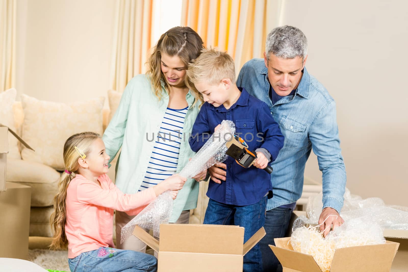 Portrait of happy family opening boxes in living room