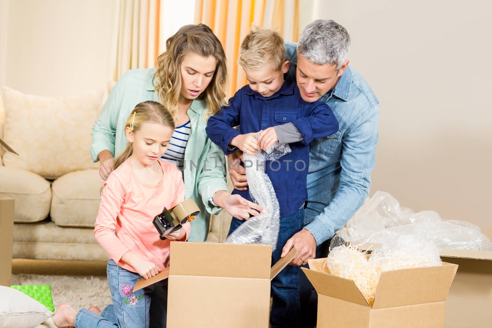 Portrait of happy family opening boxes in living room