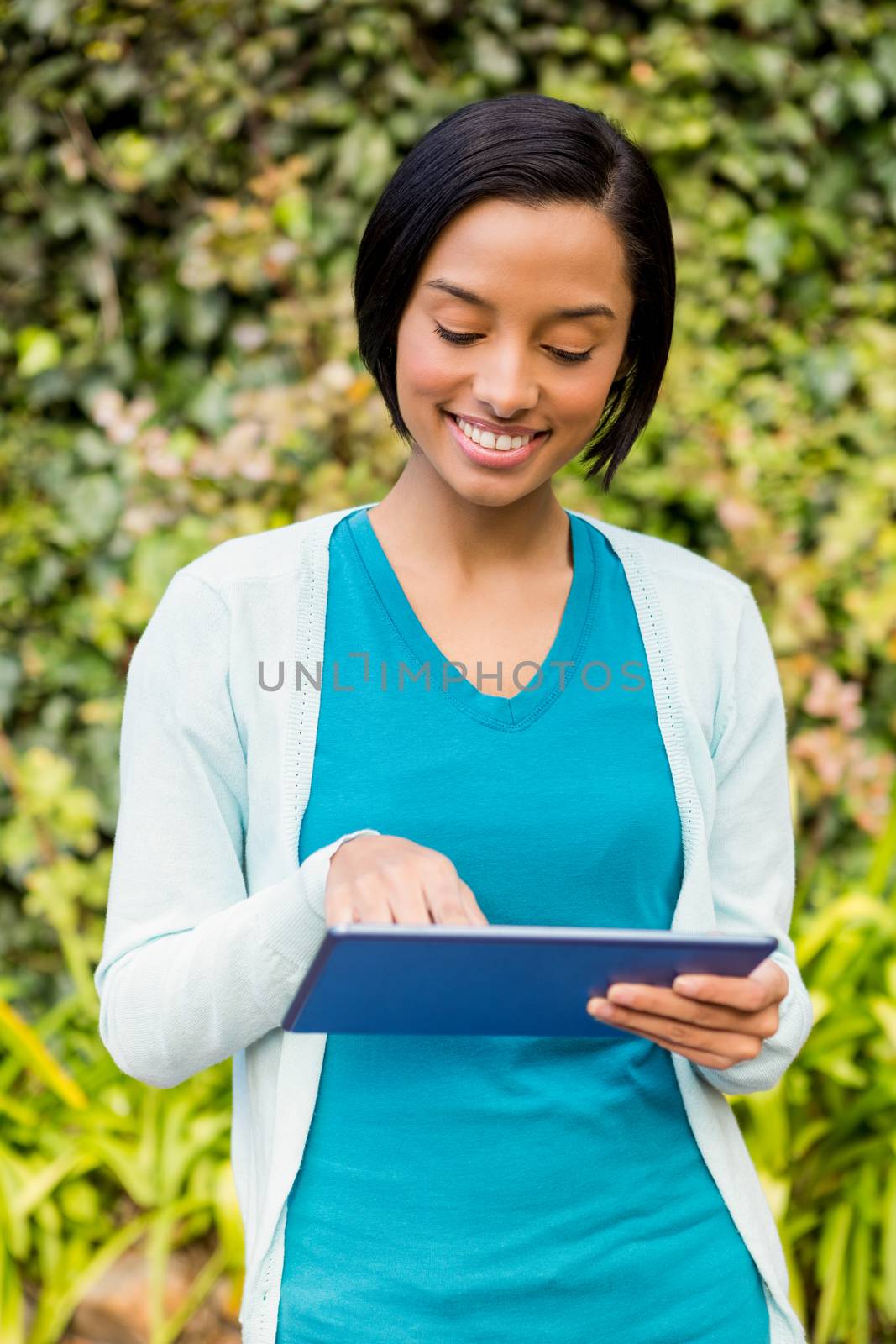 Smiling brunette using tablet outdoors