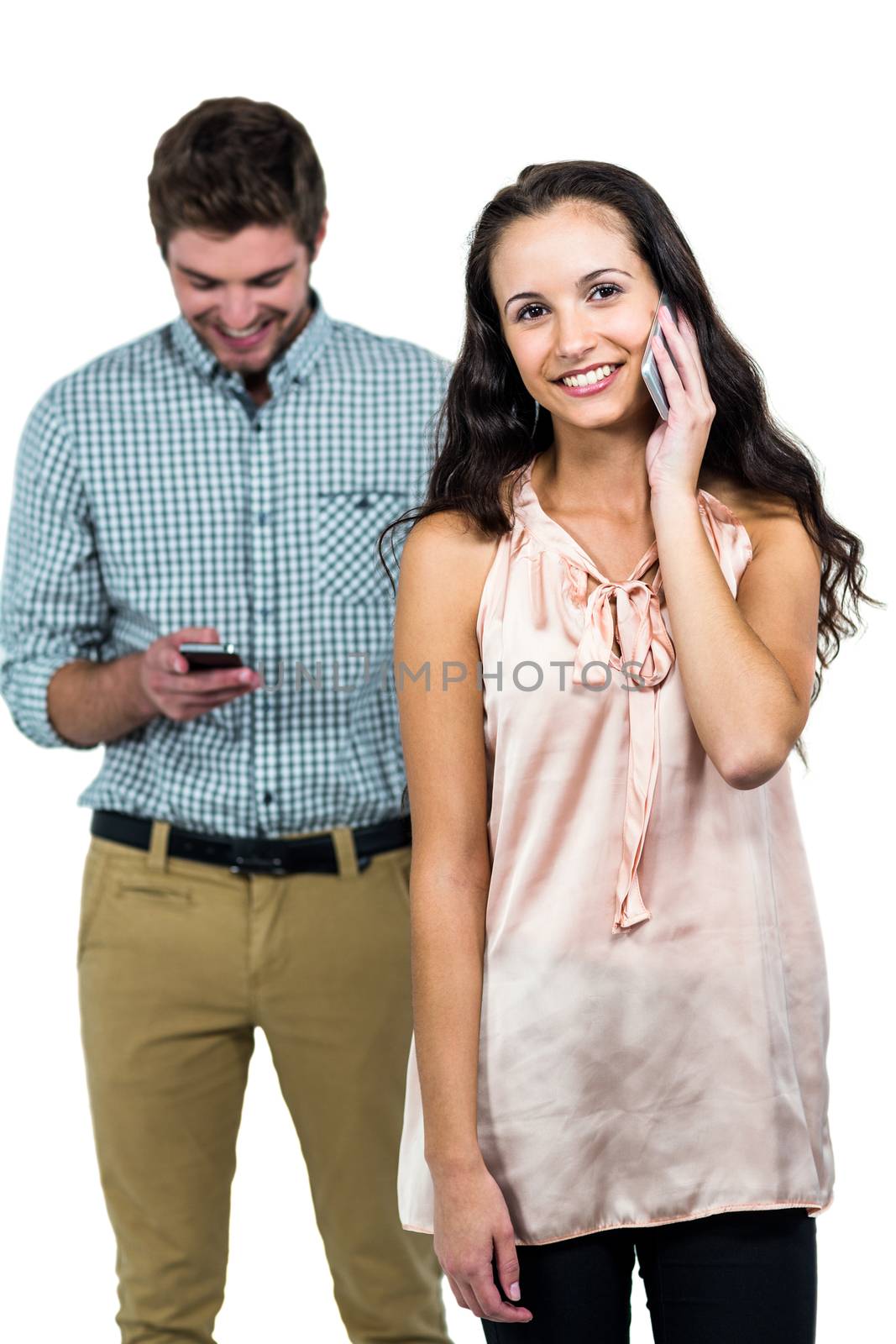 Smiling couple using smartphones by Wavebreakmedia