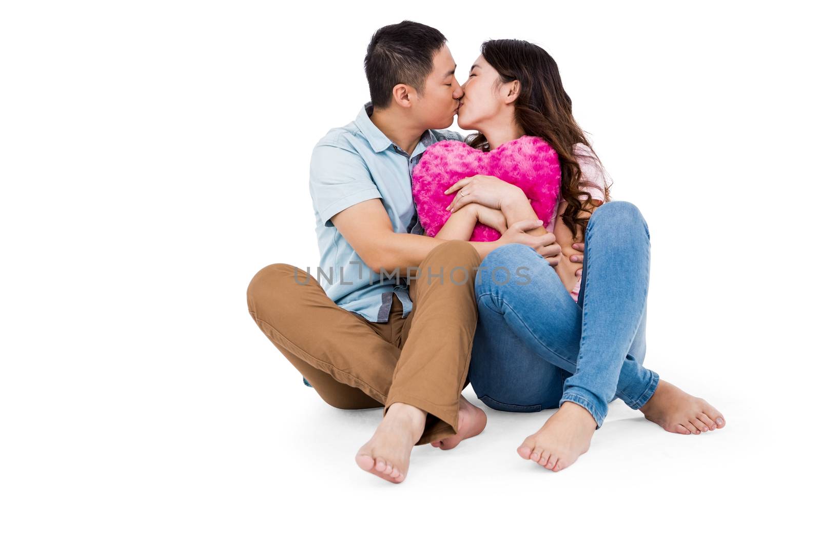 Romantic young couple kissing while sitting on white background