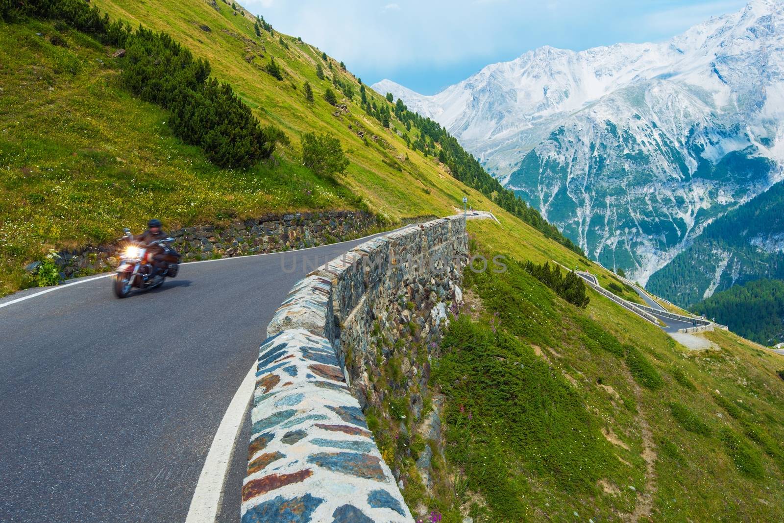 Alpine Road Biker. Motorcycle on the Stelvio Pass, Italy, Europe. Scenic Italian Mountains Road.