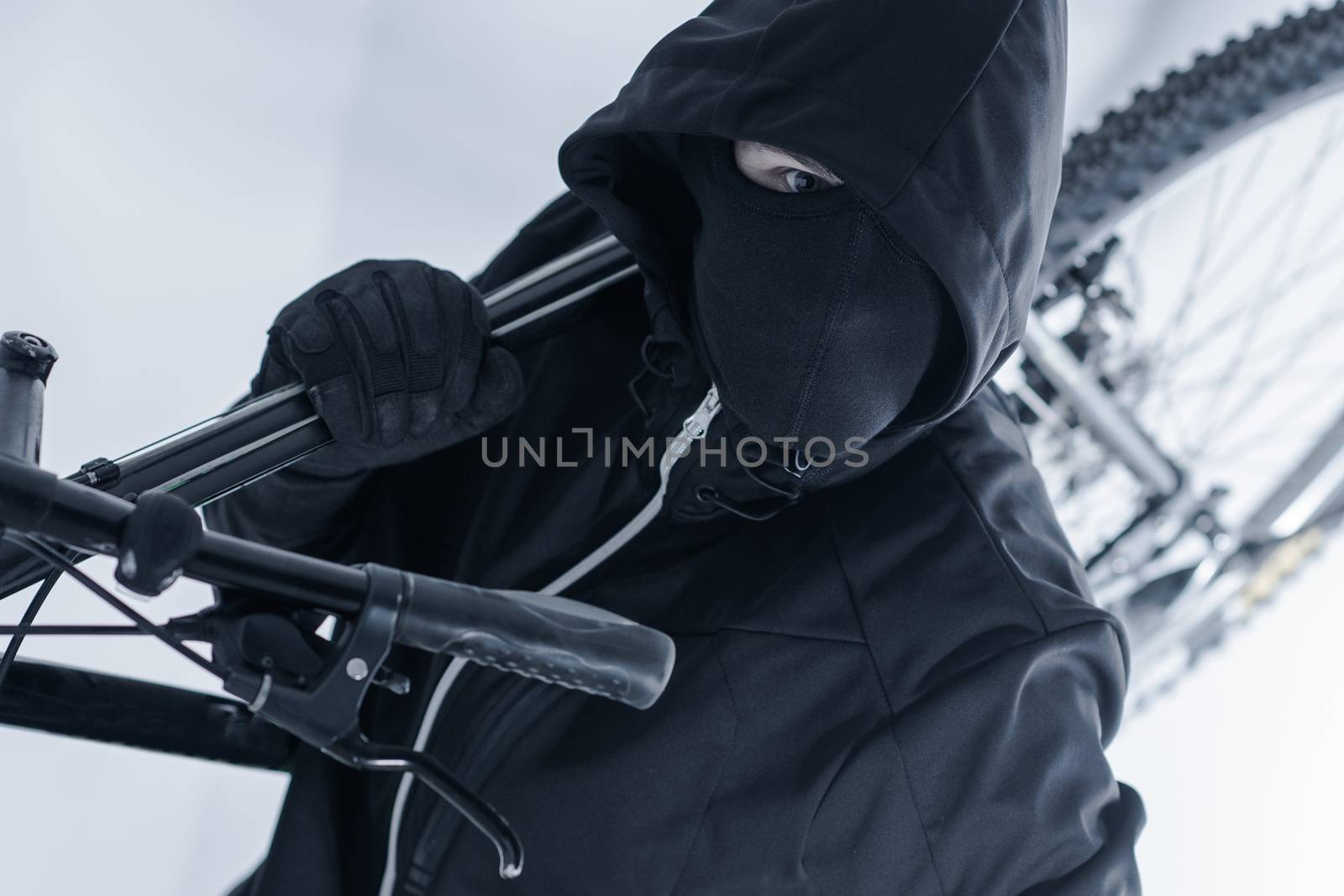 Bike Theft. Bike Thief in a Hood, Black Mask and Black Gloves. Caucasian Male Thief.