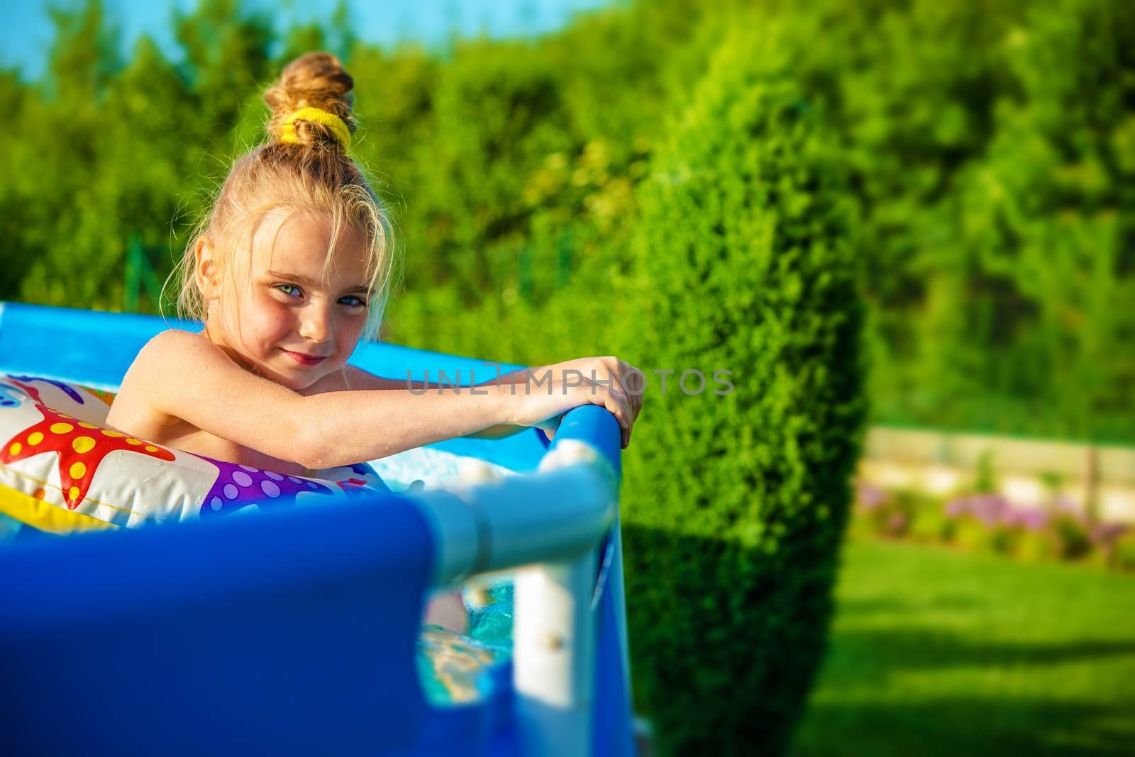 Little Smiling Girl in a Home Backyard Swimming Pool in Hot Summer Day.