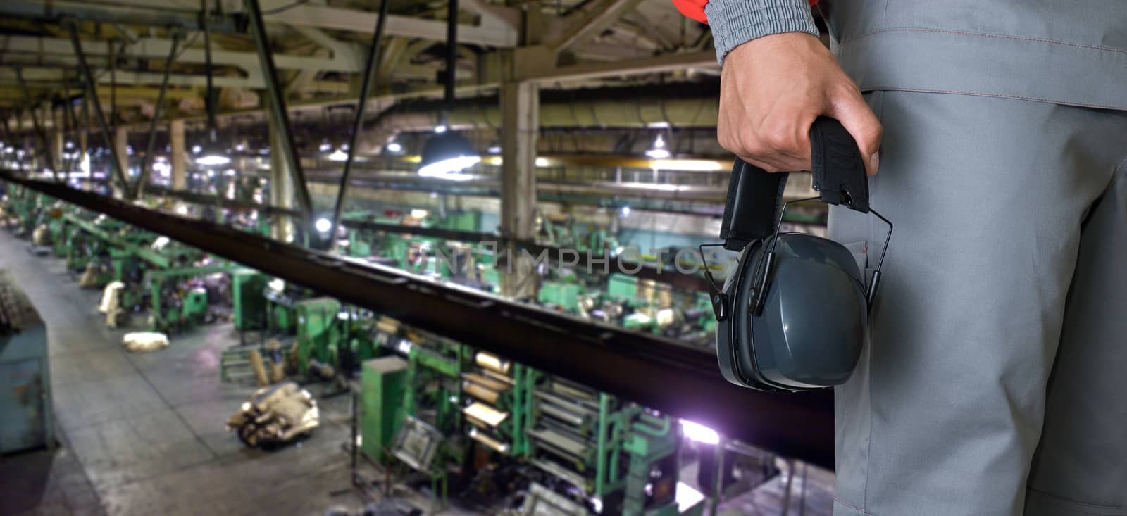 Worker with protective headphone at man hands at industrial factory