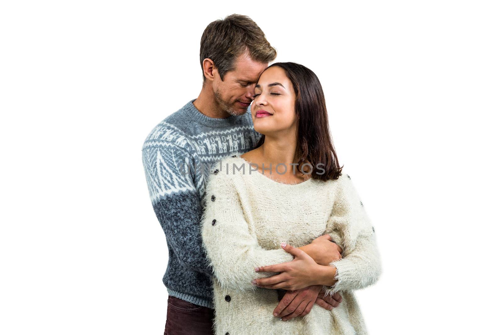 Romantic couple in warm clothing embracing against white background