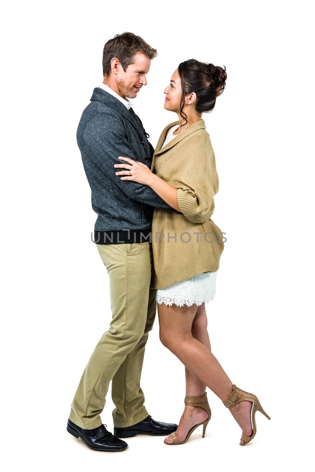 Side view of romantic couple embracing against white background