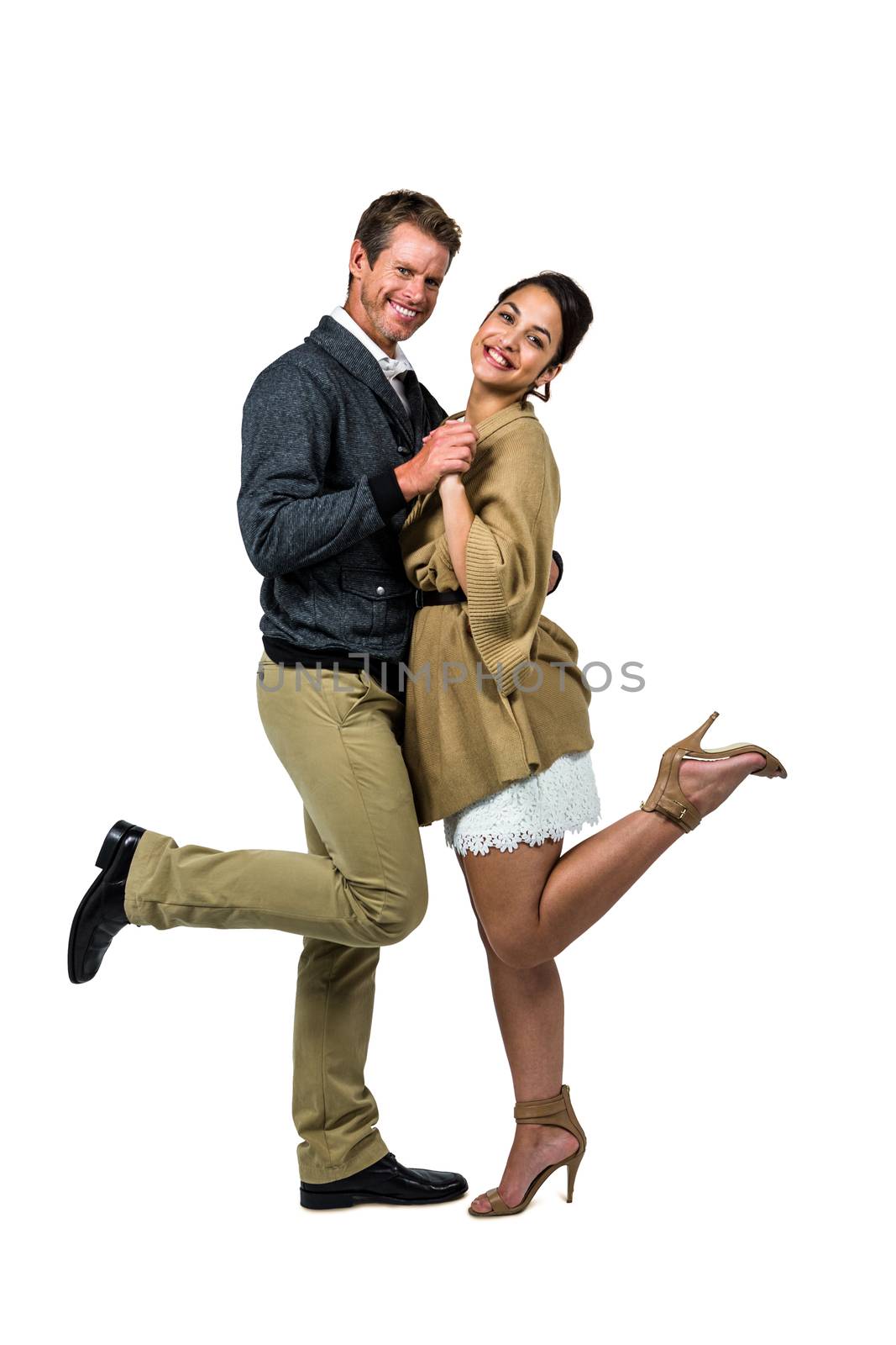 Portrait of happy romantic couple dancing against white background