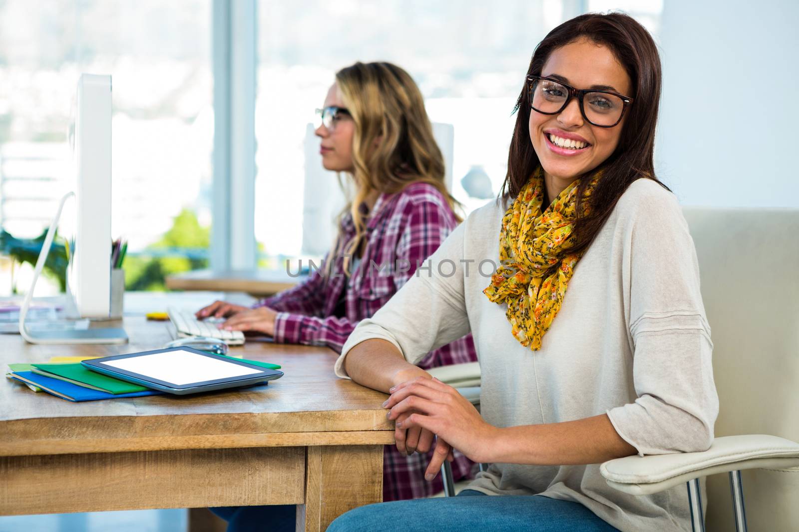 Two girls work at office on computer and tablet