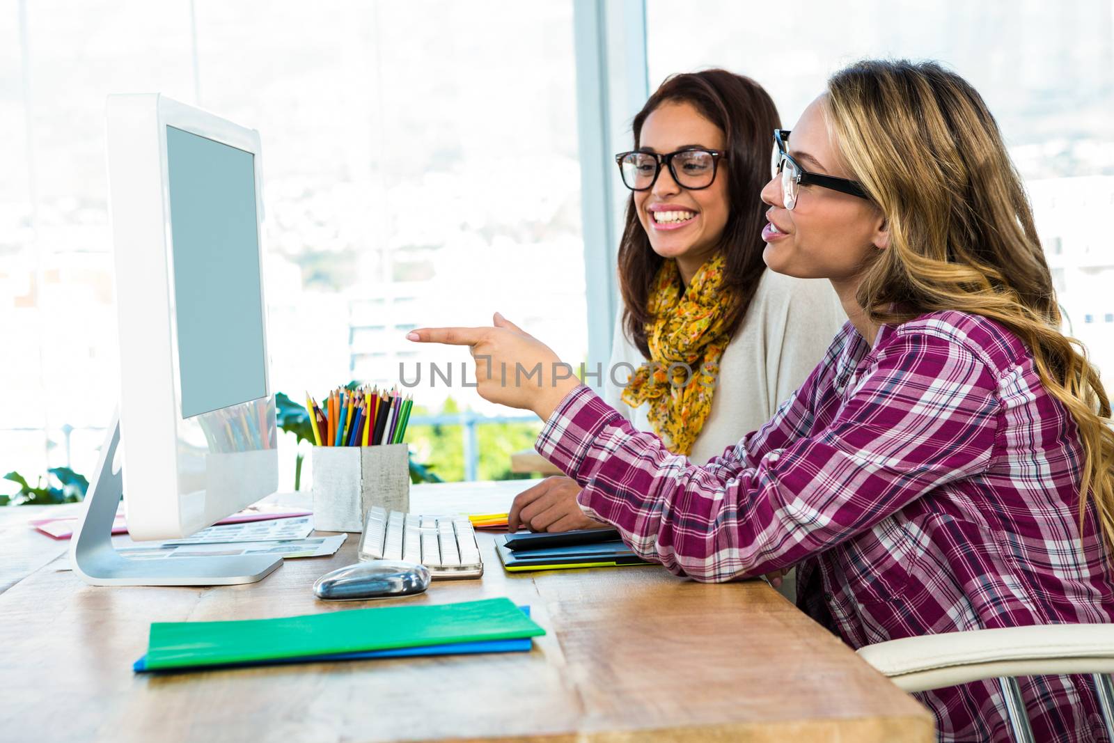 Two girls use a computer in an office