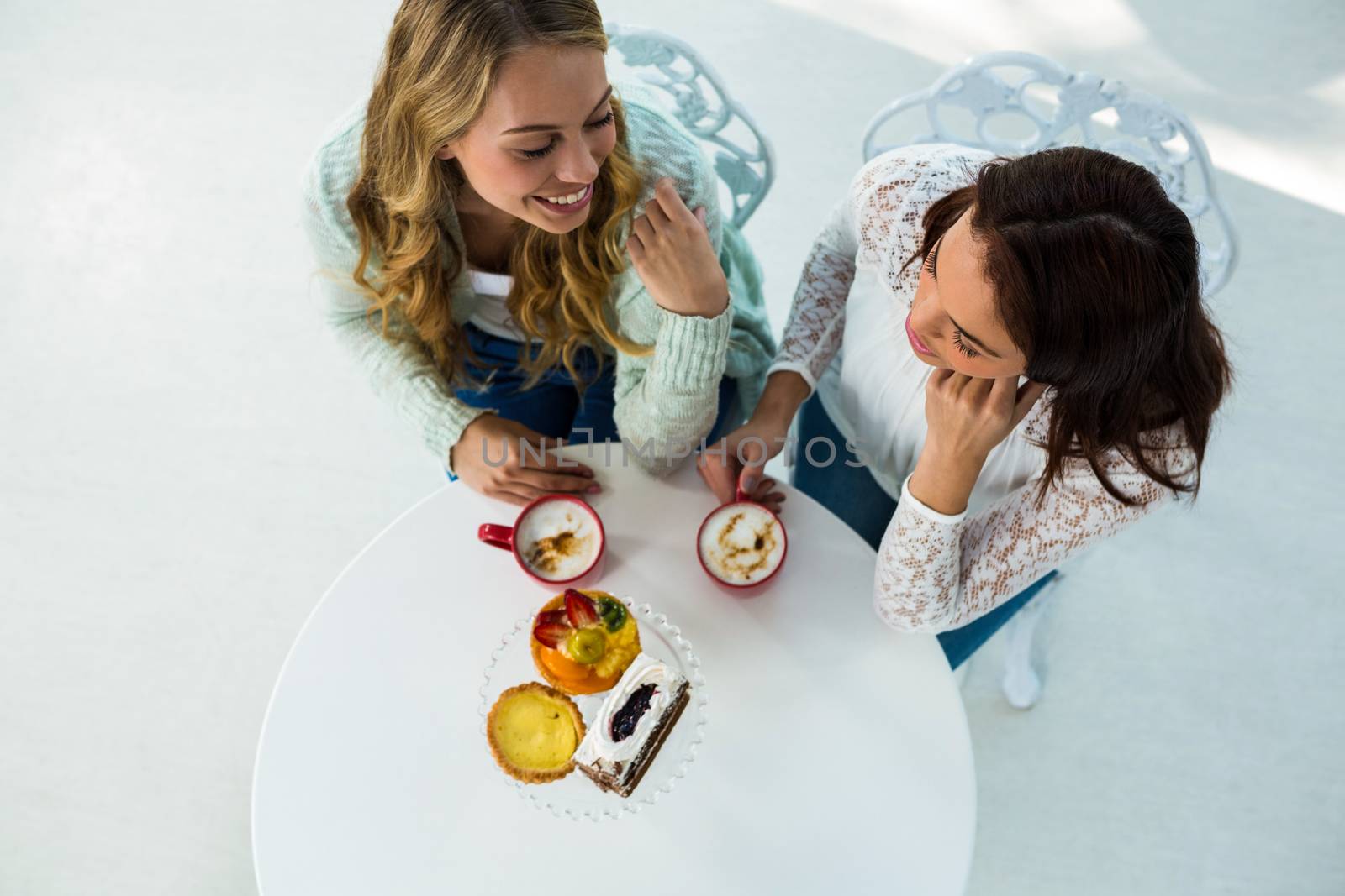 two girls drink coffee and eating pastries