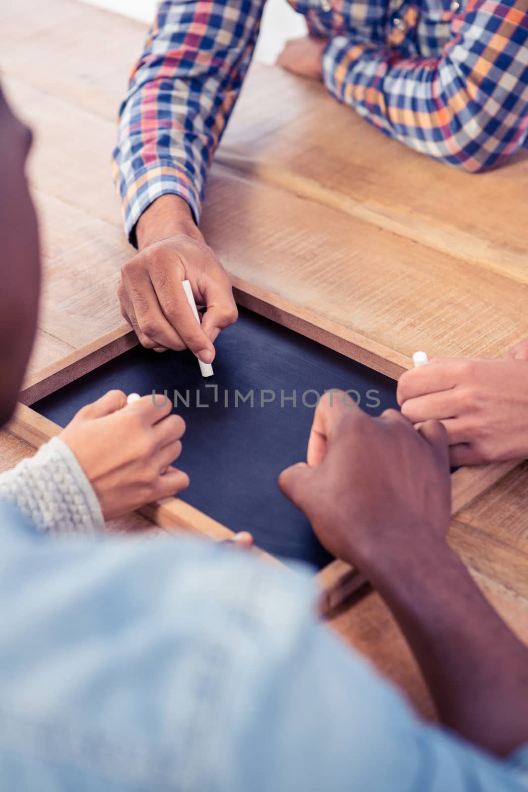 High angle view of business people writing on slate at desk in creative office