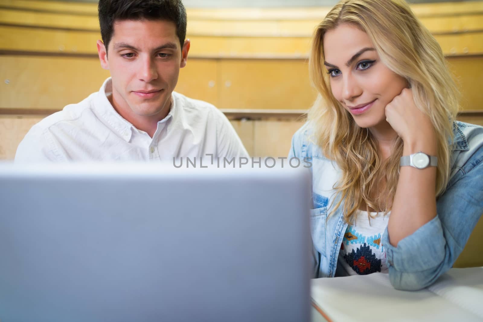 Smiling college students using laptop by Wavebreakmedia