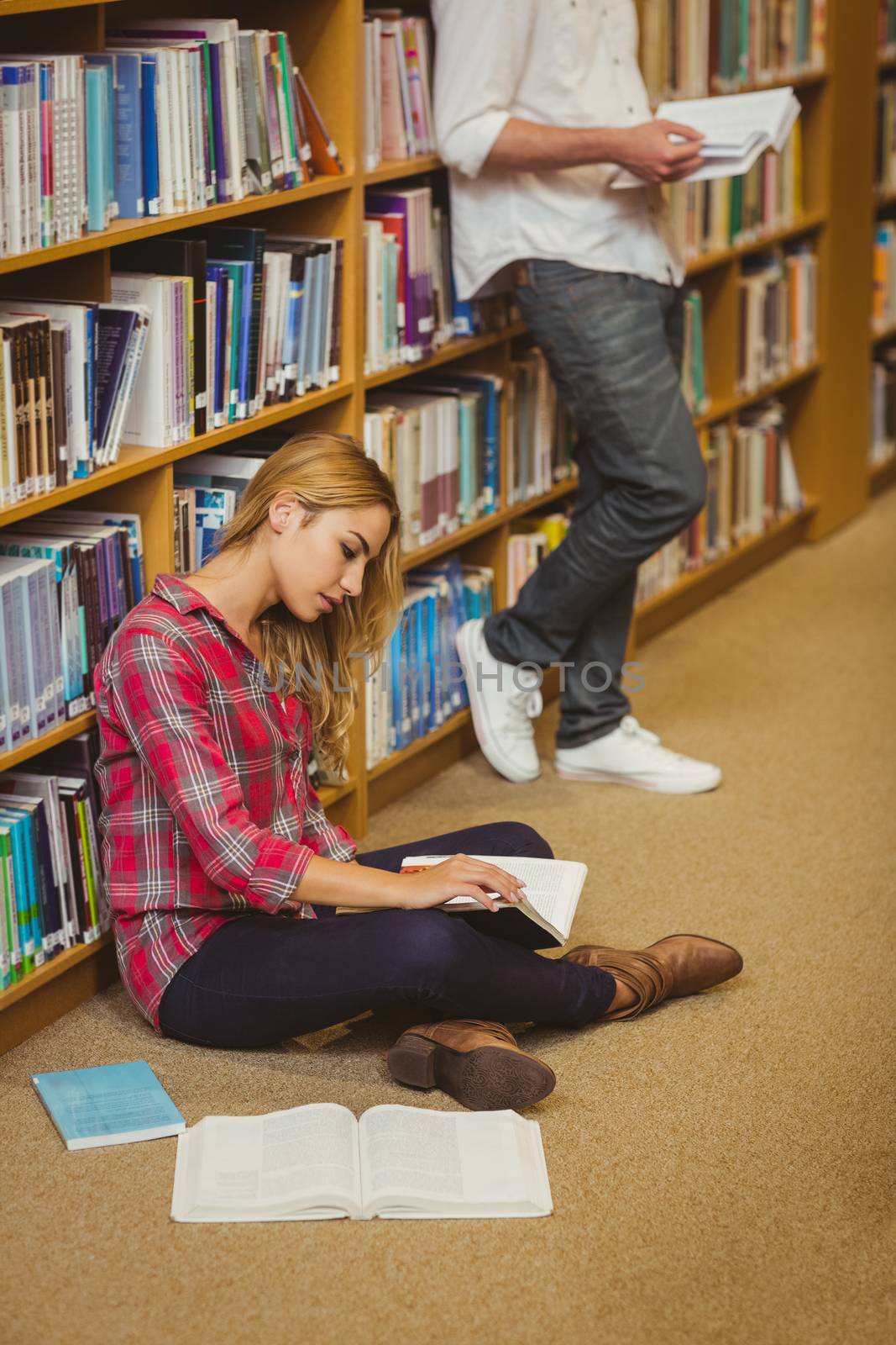 Female student working on floor in library 