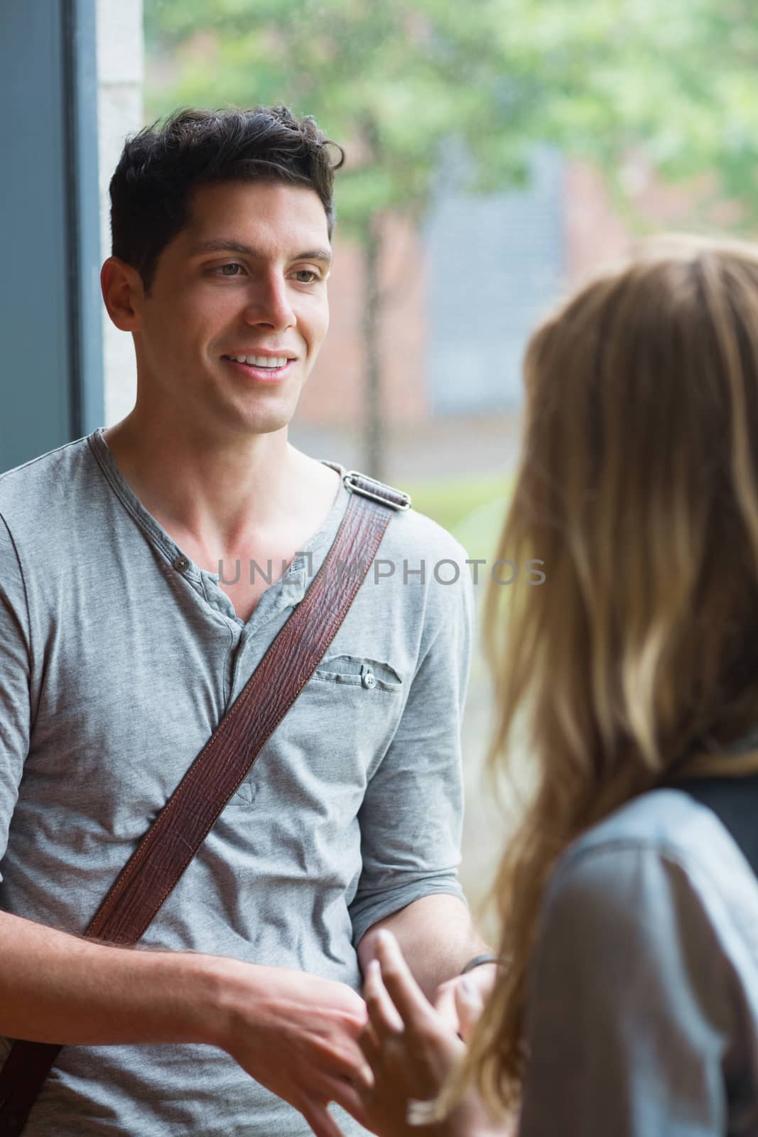 Smiling male student talking to a friend at the university