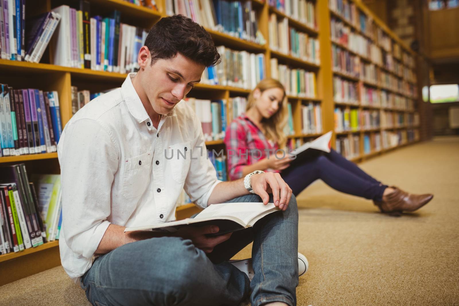 Concentrated students working on floor in library