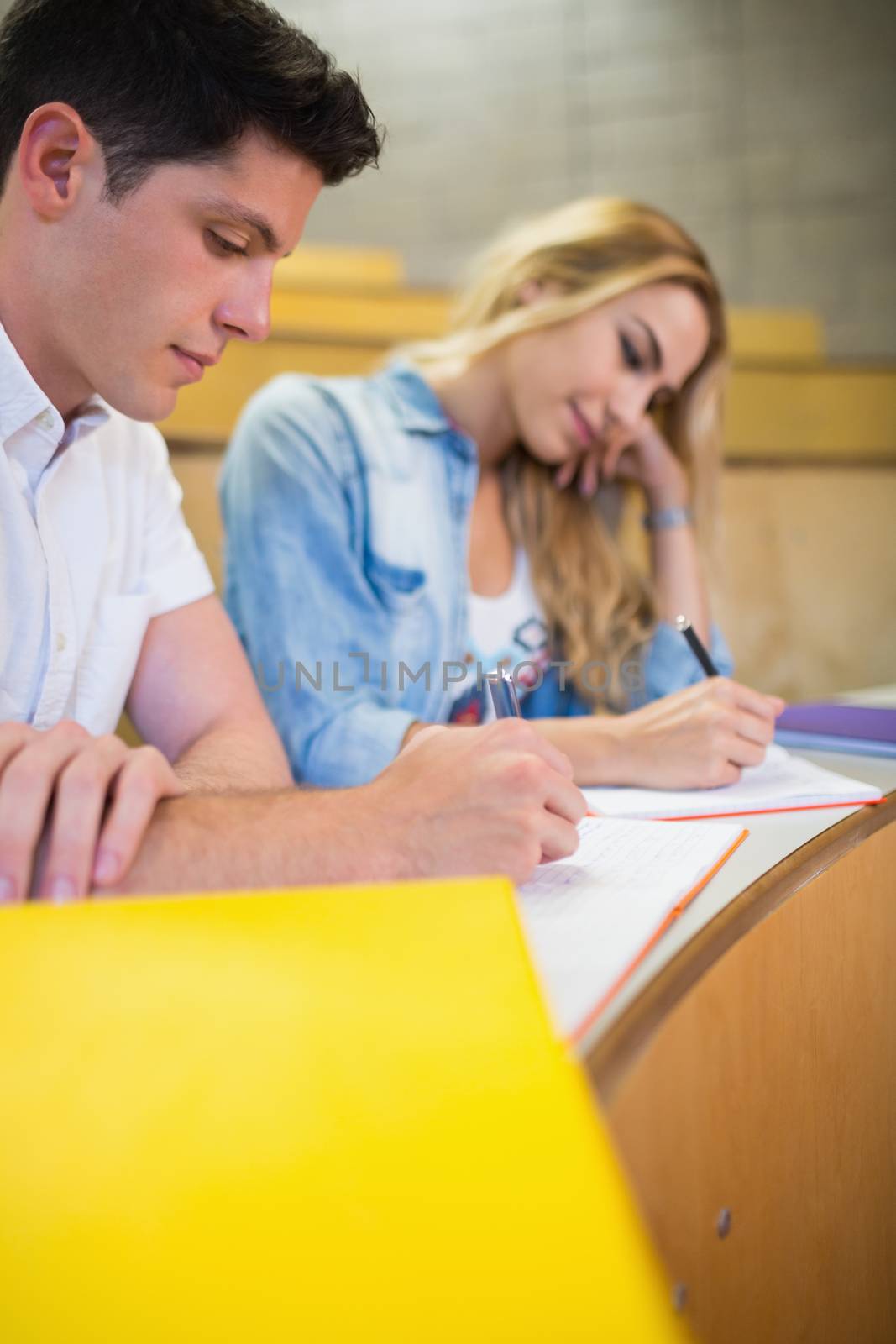 Serious students writing during class  by Wavebreakmedia