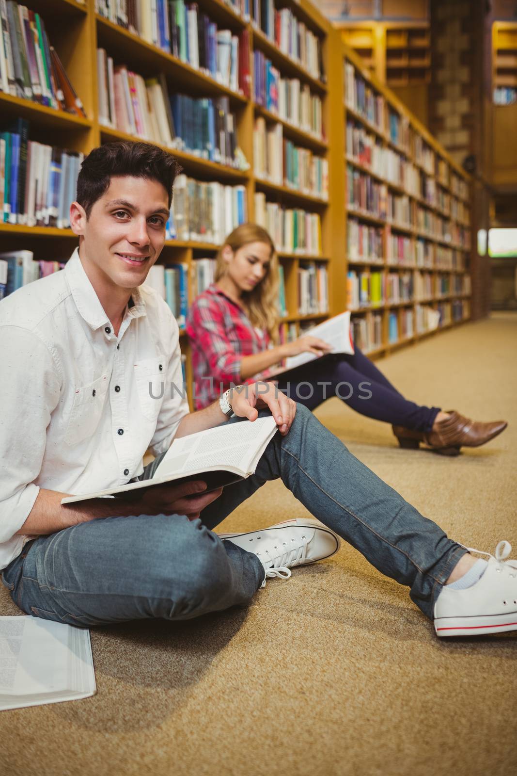 Smiling male student revising on floor by Wavebreakmedia